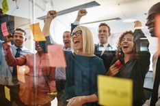 Une image d'une équipe professionnel soudé, derrière une vitre en verre avec des post-its, entrain de célébrer une inauguration de partenariat - Cowoliday