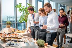 groupe de personne corporate lors d'une soirée d'entreprise, socialisant ensemble devant un buffet - Cowoliday