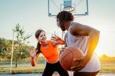 Deux personnes jouant au basket, un homme tient la balle et la jeune fille pare ses mouvement, il semble être en tournoi de basket - Cowoliday