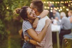 Couple fiancé s'enlaçant, en fond on voit les invités amis et famille venu célébrer les fiançailles avec le couple - Cowoliday